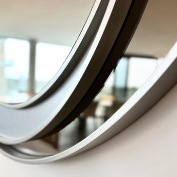 Circular wall mirror detail with a polished silver finish