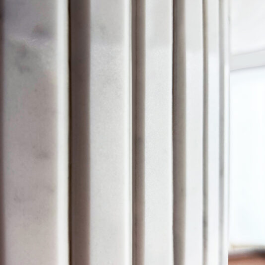 Exclusive Oval Ammonite Tuscany Quartz Dining Set Close-up of vertical white panels under soft lighting with a blurred background; these stylish panels complement the Exclusive Oval Ammonite Tuscany Quartz Dining Suite in a refined interior.