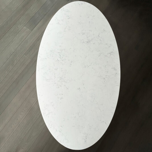 Exclusive Oval Ammonite Tuscany Quartz Dining Table The Exclusive Oval Ammonite Tuscany Quartz Dining Table features a white marble top, showcased from above against a dark wooden floor with distinct grain and plank patterns.