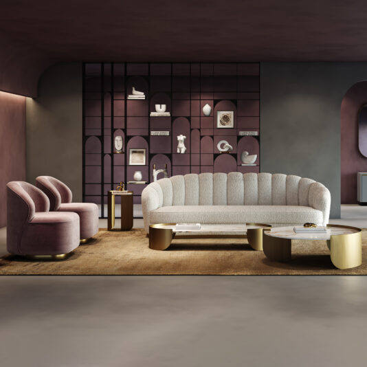 Modern living room with a Large Modern Velvet Sofa, two mauve armchairs, gold-accented coffee and side tables, a brown rug, and a wall shelving unit displaying decor and art.