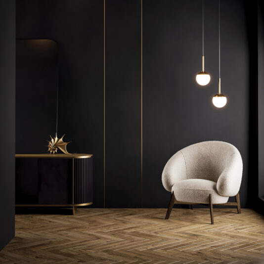 A modern minimalist room with dark walls, a Mid-Century Style Italian Armchair, two globe pendant lights, a wooden sideboard topped with a gold abstract sculpture, and herringbone-patterned wooden flooring.