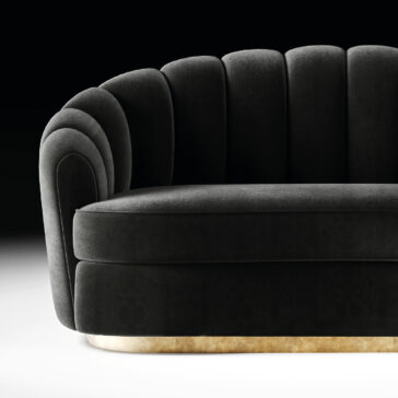 Modern Velvet Sofa The Modern Velvet Sofa features black velvet upholstery, a scalloped shell-like backrest, curved armrests, and a metallic gold base, offering elegant luxury against a dark backdrop.