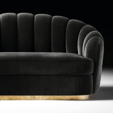 Modern Velvet Sofa The Modern Velvet Sofa, upholstered in black velvet with a scalloped art deco-style backrest and gold-coloured base, stands out against a plain black background.