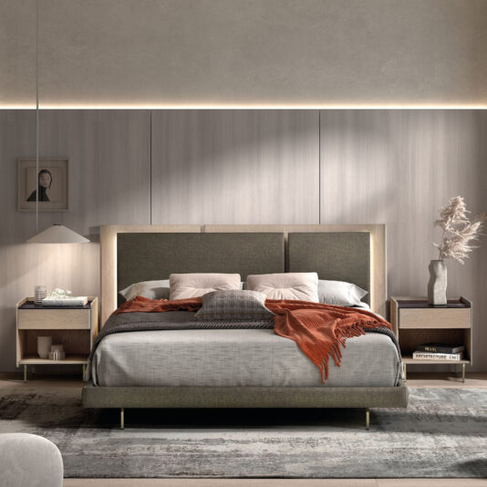 Contemporary Bed With Backlit Headboard A modern bedroom showcases the Contemporary Bed With Backlit Headboard, grey upholstery, white and grey bedding, and an orange throw. Two bedside tables display books, a lamp, and a vase with dried plants, all softly lit to enhance the neutral décor.