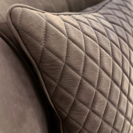 Contemporary Nubuck Leather Swivel Armchair Close-up of a brown, quilted cushion with diamond pattern and visible stitching, highlighting the craftsmanship and plush texture of the Contemporary Nubuck Leather Swivel Armchair.