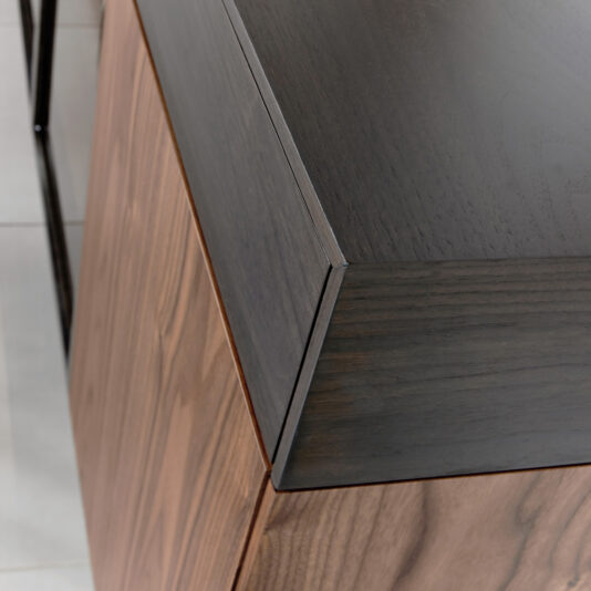 Close-up of the Modern 4 Door Walnut Veneer Sideboard, featuring a dark top and lighter wood sides with clean lines and smooth finishes, shown on a tiled floor.