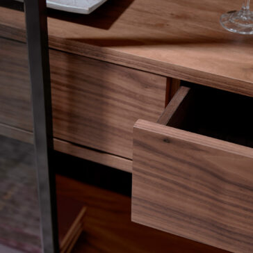 Modern Walnut Veneer Display Cabinet A close-up of the Modern Walnut Veneer Display Cabinet with an open drawer reveals the wood grain, whilst a glass and plate rest partially visible on its surface.