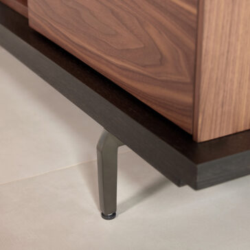 A close-up of the Modern Walnut Veneer TV Cabinet with metal legs on a light tiled floor, showing its dark base and elegant wood grain pattern on the side.
