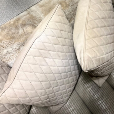 Close-up of the Set of 4 Quilted Nubuck Scatter Cushions in light beige, featuring a diamond-stitched pattern, arranged on a textured sofa with a soft rug in the background.