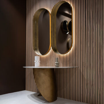 Contemporary Pill Wall Mirror A modern bathroom vanity features a curved bronze base, a white countertop inspired by the Modern Marble Console Table, and two large backlit oval mirrors on a vertical wooden slat wall.