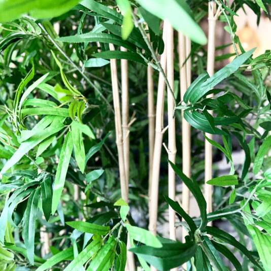 Set Of 2 Artificial Bamboo Planter Screens Close-up of thin bamboo stems and lush, narrow green leaves, accented by the elegant Faux White Agapanthus in Glazed Bowl (Copy) nestled among the vibrant foliage.