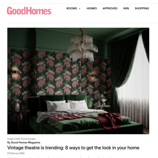 A luxurious bedroom with green velvet bed, floral wallpaper, dark green curtains, and an ornate chandelier, featured on the GoodHomes website article about vintage theatre-inspired home décor.