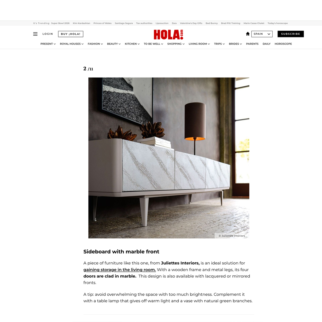 A modern sideboard with a marble-patterned front stands against a wall, topped with decorative items and a round brown table lamp. The setting is a stylish, well-lit living room with neutral tones.