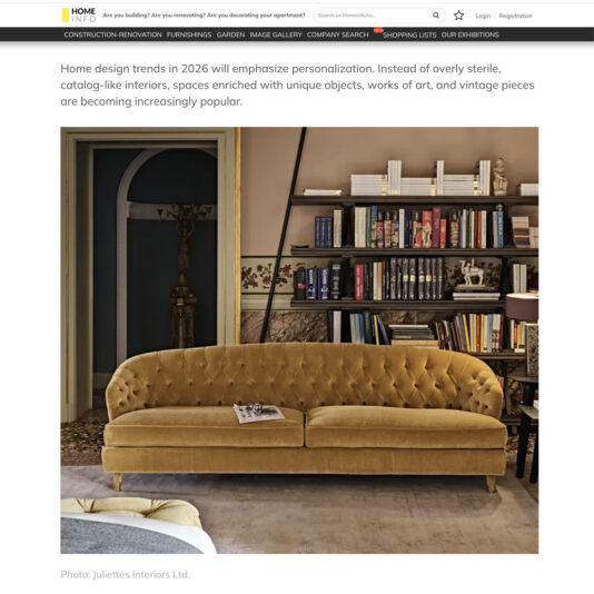 A living room with a gold velvet sofa, circular side table, and decorative objects on a shelf. The room has arched doorways, taupe walls, and vintage-inspired décor.