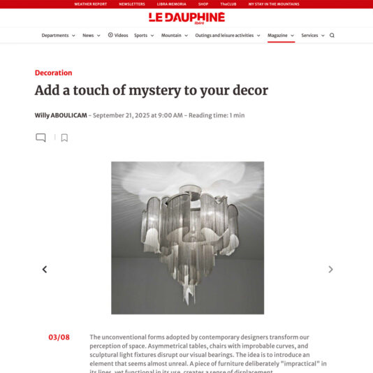 A modern chandelier with cascading metallic chains hangs from the ceiling, illuminated softly. The image appears on a webpage with the headline "Add a touch of mystery to your décor" by Le Dauphiné.