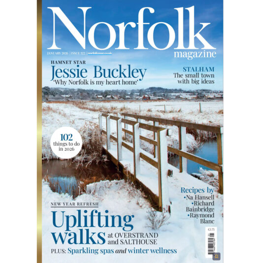 Cover of Norfolk Magazine featuring a snowy landscape with a wooden bridge over a stream. Headlines mention Jessie Buckley, uplifting walks, spas, winter wellbeing, and recipes, with pale blue and white theme.
