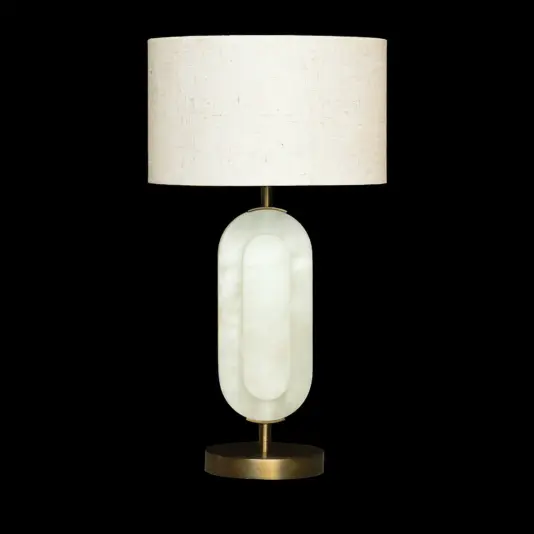 The Opal Elipse Step Table Lamp has a cylindrical off-white fabric shade, an oval frosted glass base, and a round brass stand on a black background.