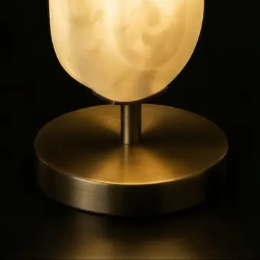 Modern Step Table Lamp A close-up of the Opal Elipse Step Table Lamp, showcasing its round brushed brass base and softly glowing marble-patterned glass shade against a dark backdrop.