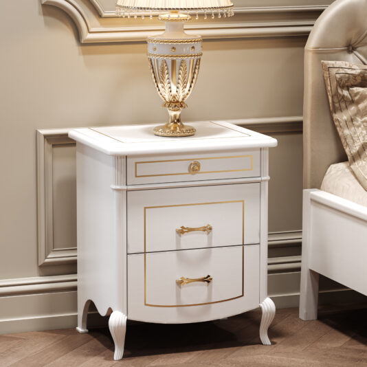 A Classic Style Lacquered Bedside Cabinet in white and gold, featuring three drawers, stands by a bed with a matching ornate lamp on top, set against a beige panelled wall and dark wood flooring.