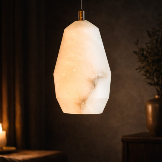 A softly glowing Natural Stone Globe Pendant Light (Copy) made of alabaster hangs in a dim, cosy room with a lit candle and potted plant in the background.