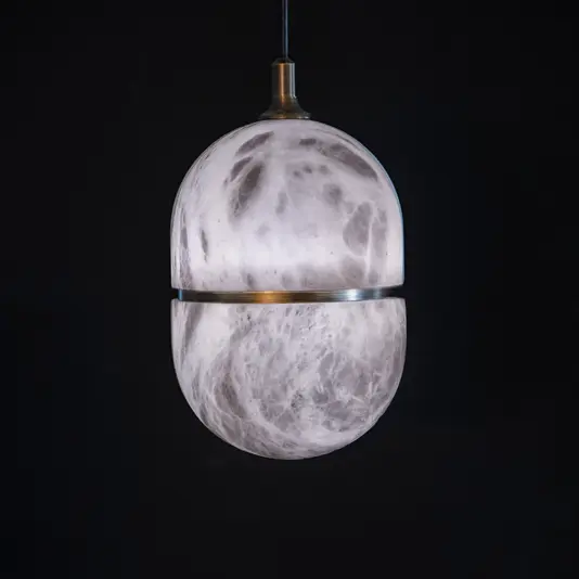 The Banded Elipse Pendant Light – Antique Brass features a marble-inspired spherical shade divided by an antique brass band, casting a soft glow and adding modern elegance to any space.