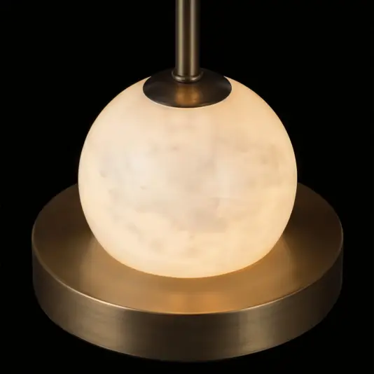 A close-up of the Opal Tall Globe with Rod Table Lamp highlights its frosted glass globe emitting a warm glow, set atop a brass base, all shown against a black background.