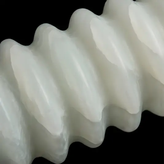 Close-up of a white, translucent, and wavy or ridged object against a black background, resembling a plastic or silicone spiral with smooth curved edges.