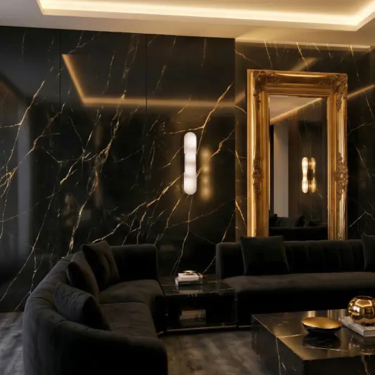 Modern lozenge shape Wall Light A luxurious living room with glossy black marble walls, a large ornate gold-framed mirror, a dark velvet corner sofa, and modern lighting, creating an elegant and sophisticated atmosphere.