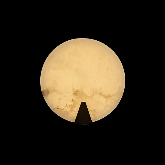 The Modern Round Wall Light features a glowing, marble-like design with a warm yellow hue, contrasted against a black background and accented by a small black triangular shape at the lower edge.