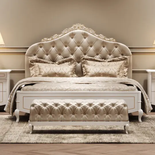 Luxurious bedroom with an ornate, tufted headboard, matching bedding, and a tufted bench at the foot of the bed. Two bedside tables with lamps flank the bed, all in soft, beige and gold tones.