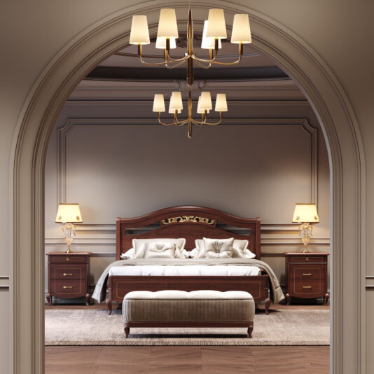 Classic Style Cherrywood Bedside Cabinet A luxurious bedroom with a wooden bed, white bedlinen, a Classic Style Cherrywood Bedside Cabinet with a lamp, a cushioned bench at the foot of the bed, and a chandelier, seen through an arched doorway.