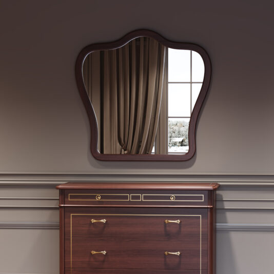The Classic Style Cherrywood Curved Mirror with wavy edges hangs above a cherrywood chest of drawers with brass handles, reflecting beige curtains and a snowy scene through the window against a grey panelled wall.