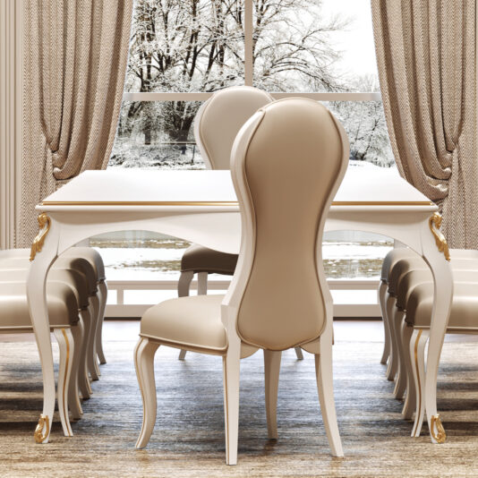 Large White Classic Style Dining Set Elegant dining room with the Large White Classic Style Dining Set—featuring a gold-trimmed table and eight beige high-backed chairs. A large window shows a snowy view, and chic décor adds to the cosy, luxurious feel.