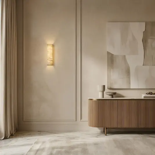 Luxury Fluted Wall Light A minimalist living room with beige walls, a Luxury Fluted Wall Light, abstract art, a wooden sideboard, a sculptural object, floor-length curtains, marble floors, and a light rug partially covering the floor.