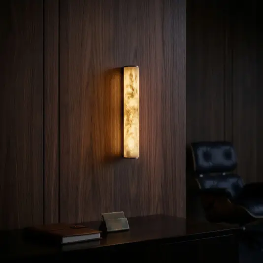 Marbled Tube Wall Light A modern, minimalist black console table with gold accents holds a black vase and a stack of books with a gold bowl on top. Above, a wood-textured wall sconce emits warm light against a dark wall.