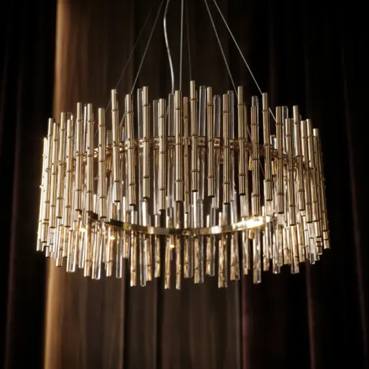 A modern circular chandelier made of numerous vertical, cylindrical gold rods, suspended by thin wires against a dark, elegant background.