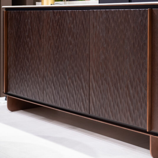 A close-up of the Contemporary Hammered Oak Veneer Sideboard featuring textured, wavy front panels, placed on a light-coloured floor.