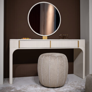 The Contemporary Lacquered Dressing Table features a round mirror, beige pouffe, two brown glass bottles, and a colourful dish, all set against a brown accent wall on a light rug.