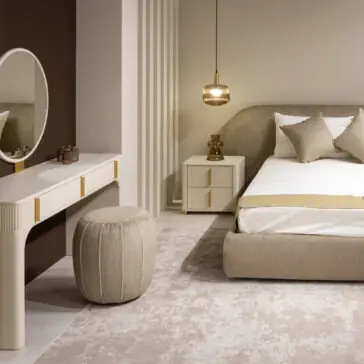 A modern, neutral-toned bedroom showcases a beige bed with pillows, a bedside table, and the Contemporary Lacquered Dressing Table set featuring a round mirror, cushioned stool, pendant lamp, and soft patterned rug.