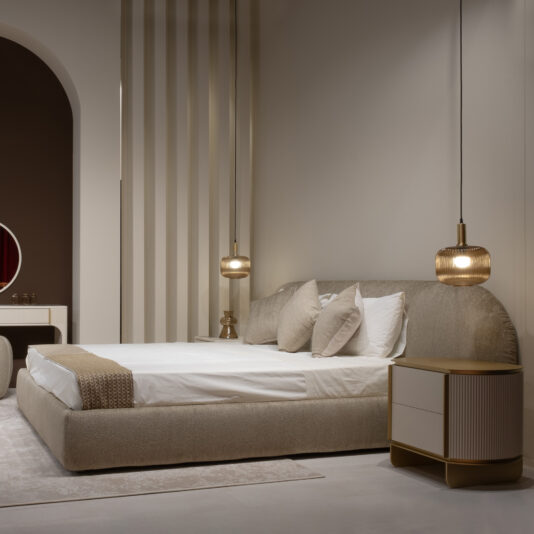A modern bedroom with a Modern Curved Upholstered Bed, crisp white bedding, neutral pillows, a gold-accented bedside table, two pendant lights, and minimalist décor bathed in soft warm light.