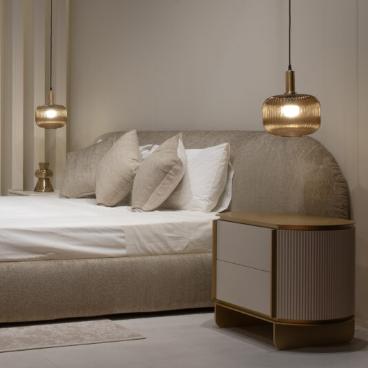 Modern Ribbed Bedside Cabinet A modern bedroom featuring a plush beige bed, white bedding, neutral pillows, and two pendant lights above the Modern Ribbed Bedside Cabinet with two drawers, creating a cosy and stylish atmosphere.