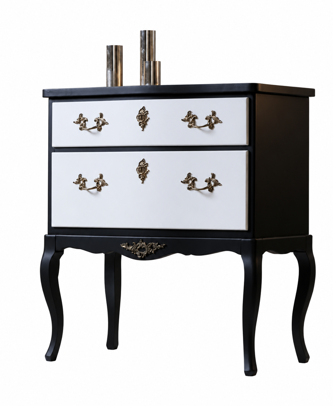 A vintage-style black and white chest of drawers with ornate handles, two drawers, curved legs, and two metallic cylindrical decorative items on top, set against a plain white background.