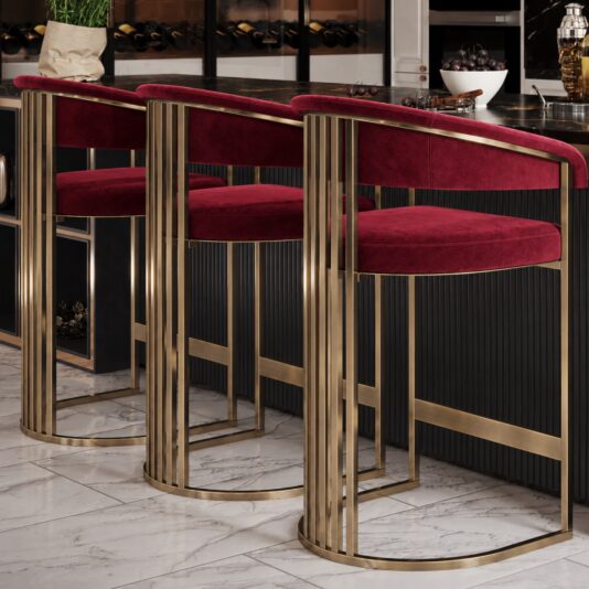 Art Deco Inspired Curved Burgundy Velvet Bar Stool Angled rear view of three curved velvet seats, vertical brushed metal bars and circular bases beside a black marble island.