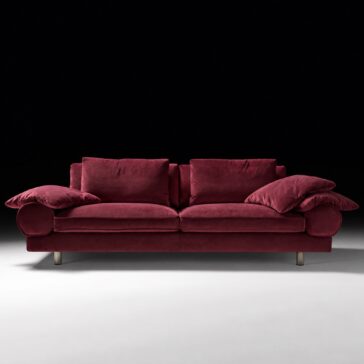 Burgundy Sofa with Retro Inspired Design Burgundy sofa with retro bolster arms, piped cushions and dark bronze legs, viewed from the front.