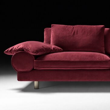 Burgundy Sofa with Retro Inspired Design Rounded left bolster arm, piped seat cushion and bronze-finish leg beneath deep wine cotton fabric.