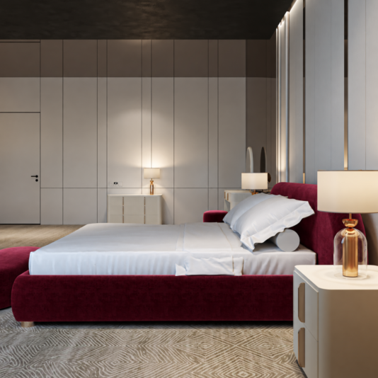 Curved Contemporary Burgundy Velvet Bed Side profile of the padded frame and rounded headboard beside a white cabinet and sculptural table lamp.