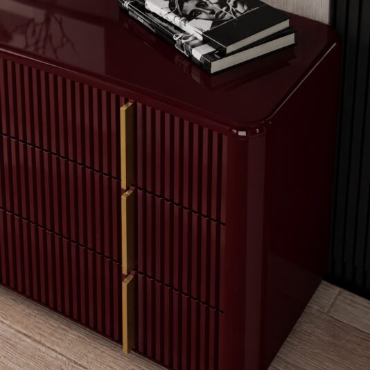 Burgundy Gloss Ribbed Chest of Drawers Close-up of the burgundy ribbed chest of drawers showing its glossy corner and gold-finished handles