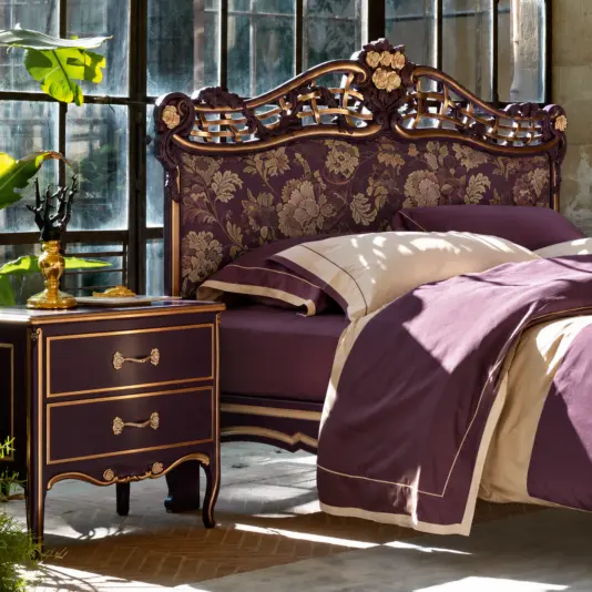 Deep Amethyst Whimsigothic Italian Bed Carved deep amethyst Italian bed with floral upholstered headboard beside a two-drawer cabinet