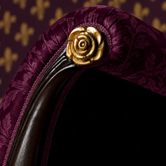 Reproduction whimsygothic Chaise Longue Close-up of gold rose carving, plum botanical upholstery and dark wood on the chaise longue