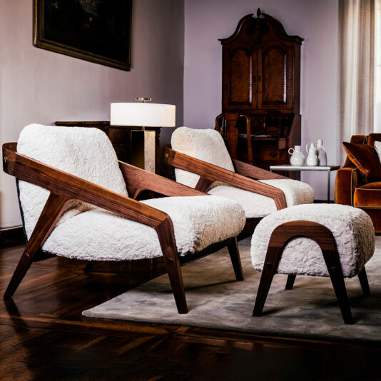 Retro interior design featuring sculptural timber-framed armchairs and a matching upholstered footstool from Juliettes Interiors